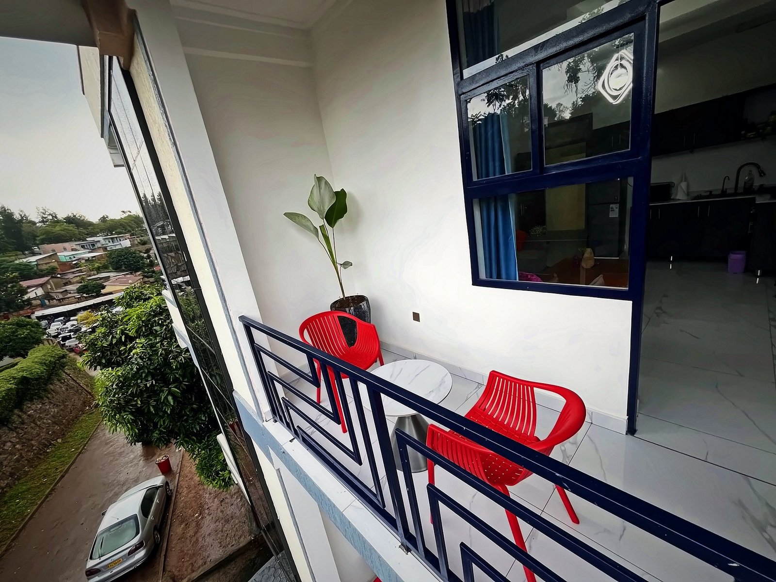 Balcony with red chairs overlooking green Kigali hillsides from Holy Apartments