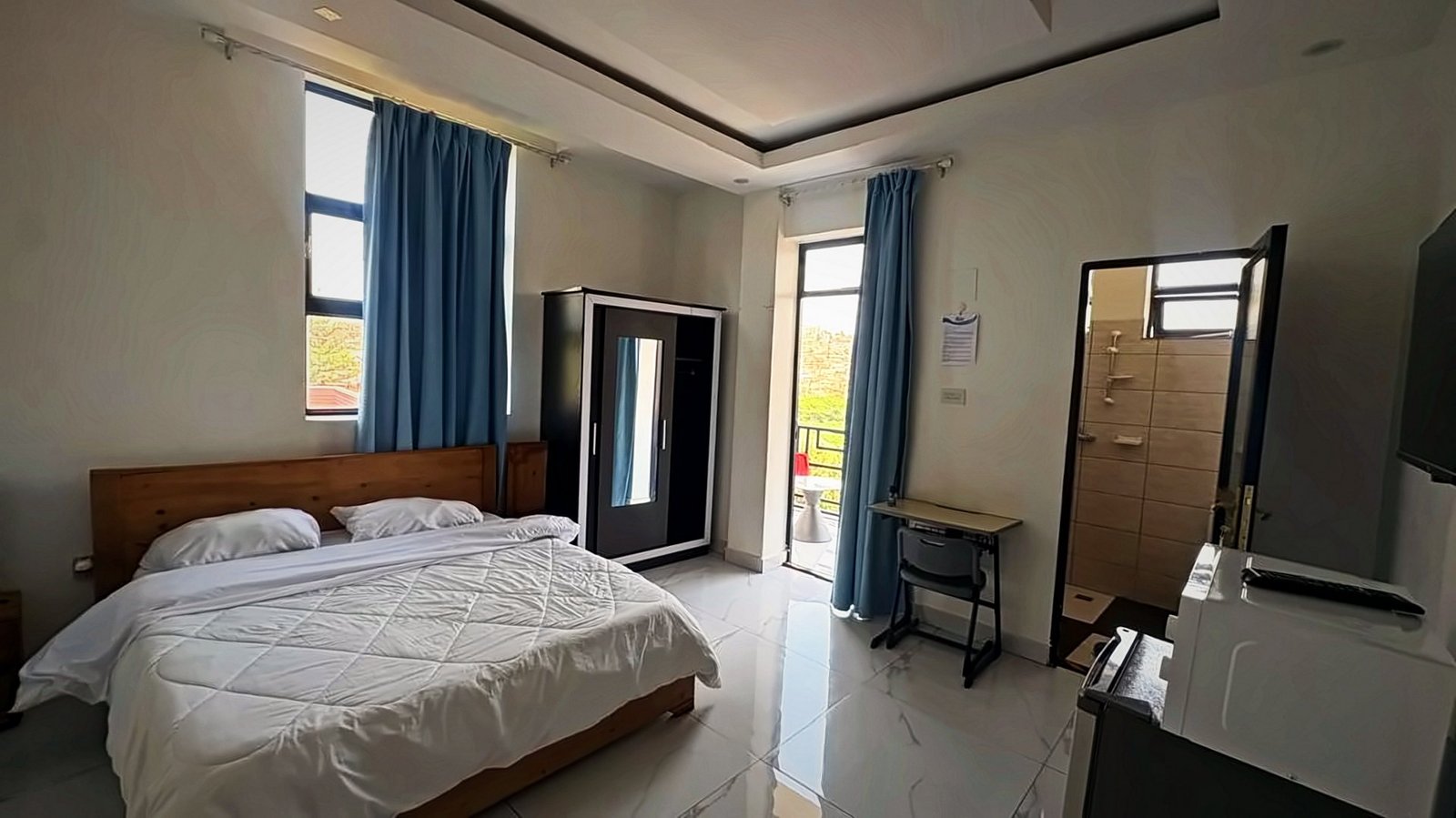 Bedroom with a double bed, blue curtains and a wardrobe at Holy Apartments, Kigali