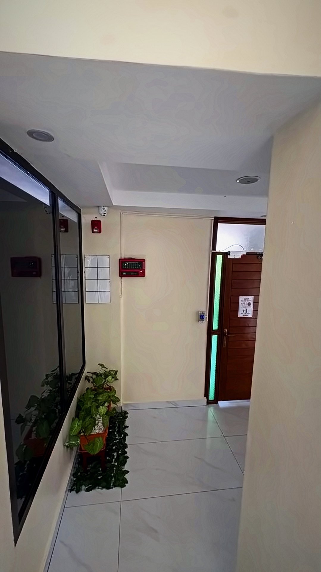 Bright corridor with a glass wall and plants at Holy Apartments, Kigali