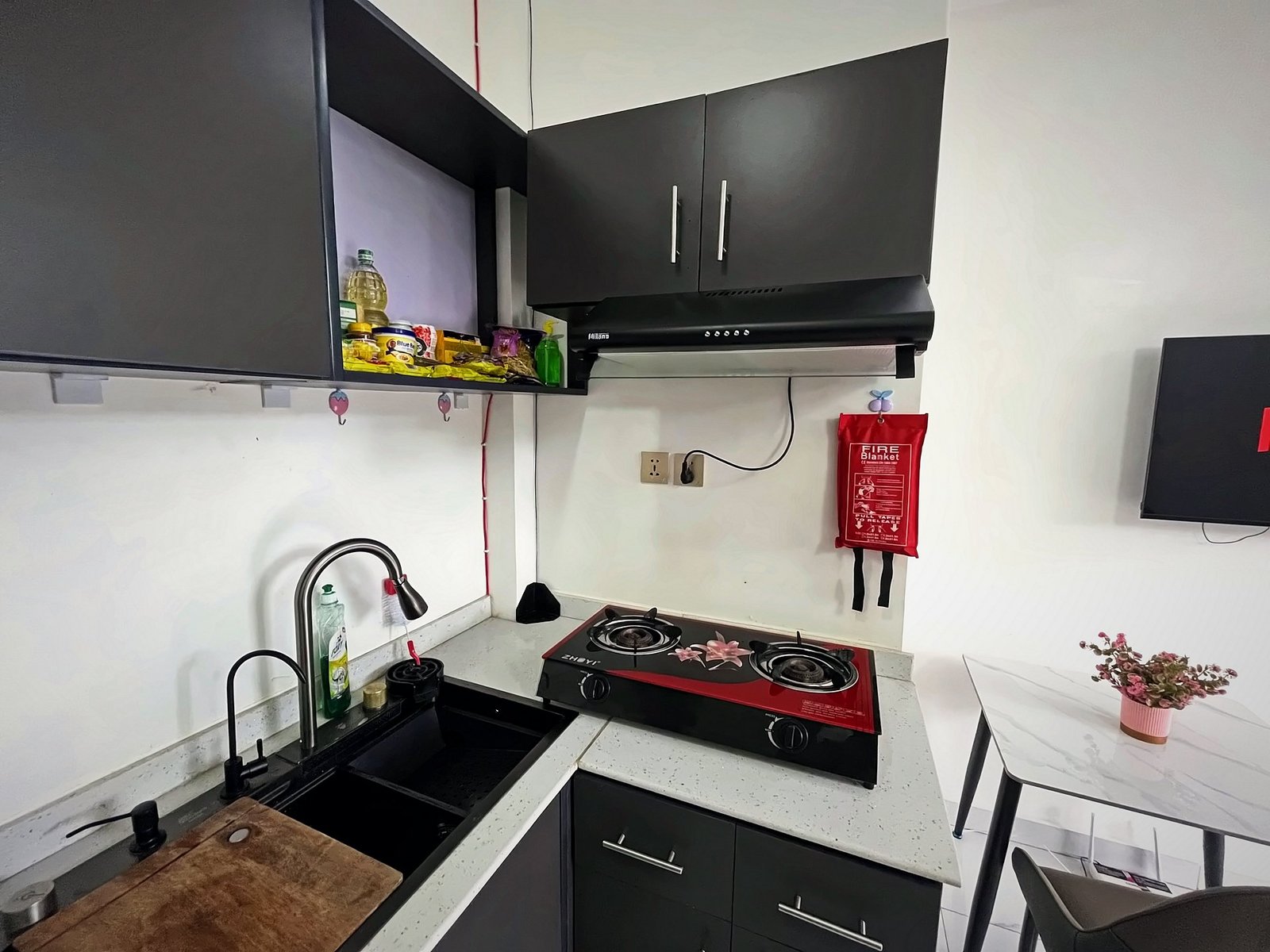 Kitchen corner with a two-burner gas hob, extractor hood and sink at Holy Apartments, Kigali
