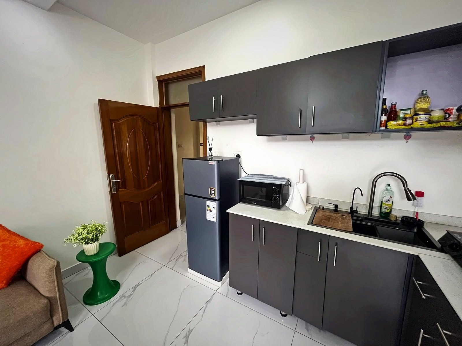 Fitted kitchen with dark cabinets, a fridge, microwave and double sink at Holy Apartments, Kigali