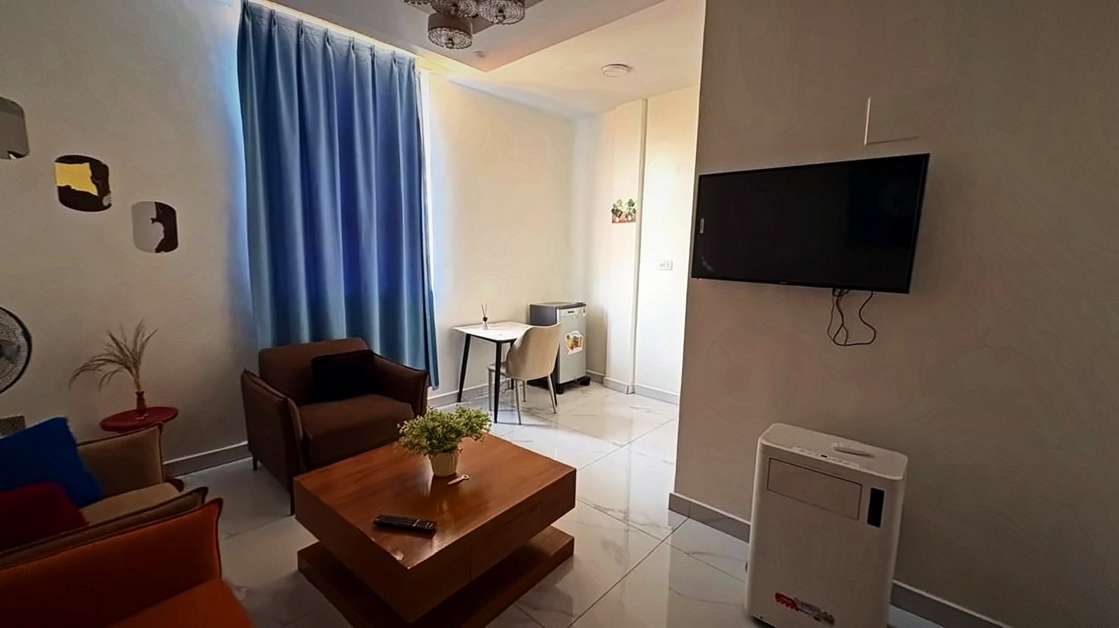 Living room with an orange sofa, TV and a small dining table at Holy Apartments, Kigali