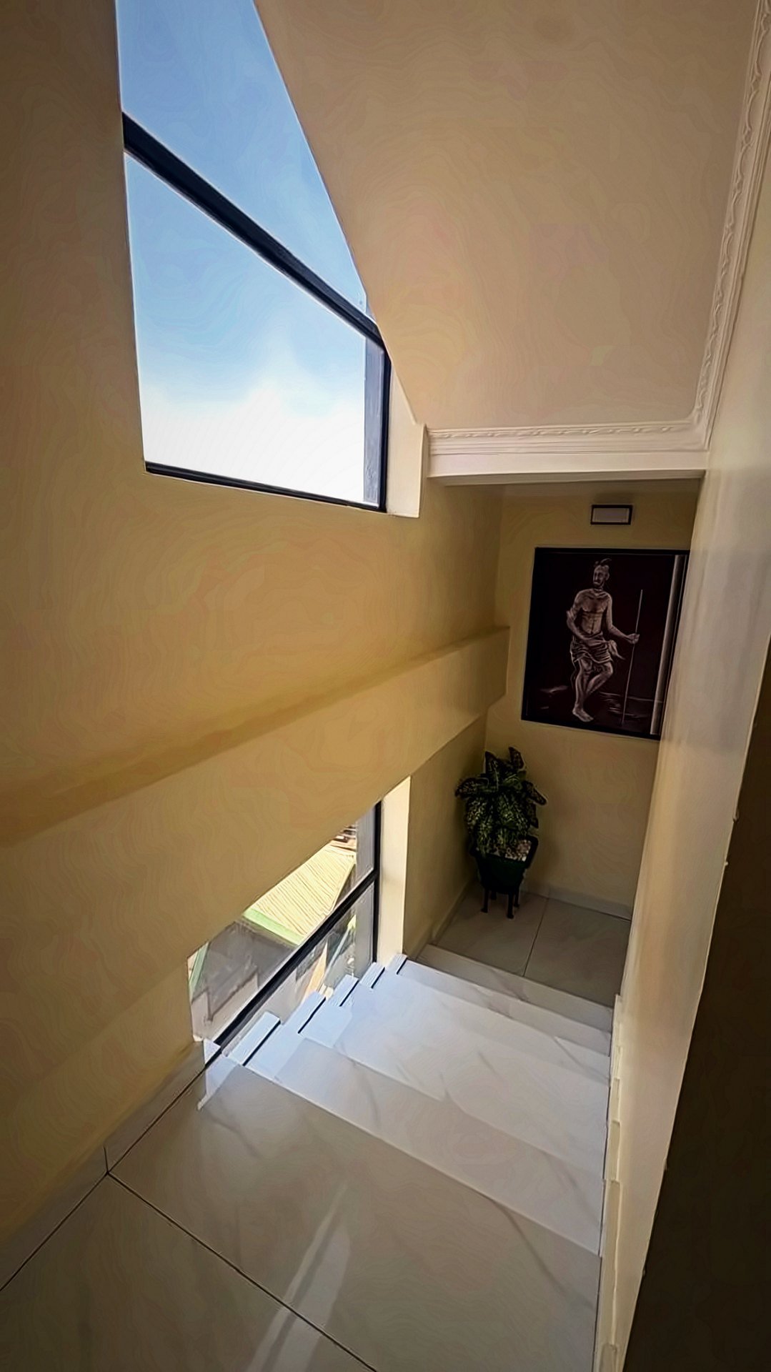 Marble stairs with a large window and artwork at Holy Apartments, Kigali