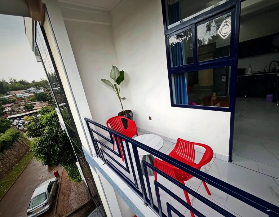 Balcony with red chairs overlooking green Kigali hillsides from Holy Apartments