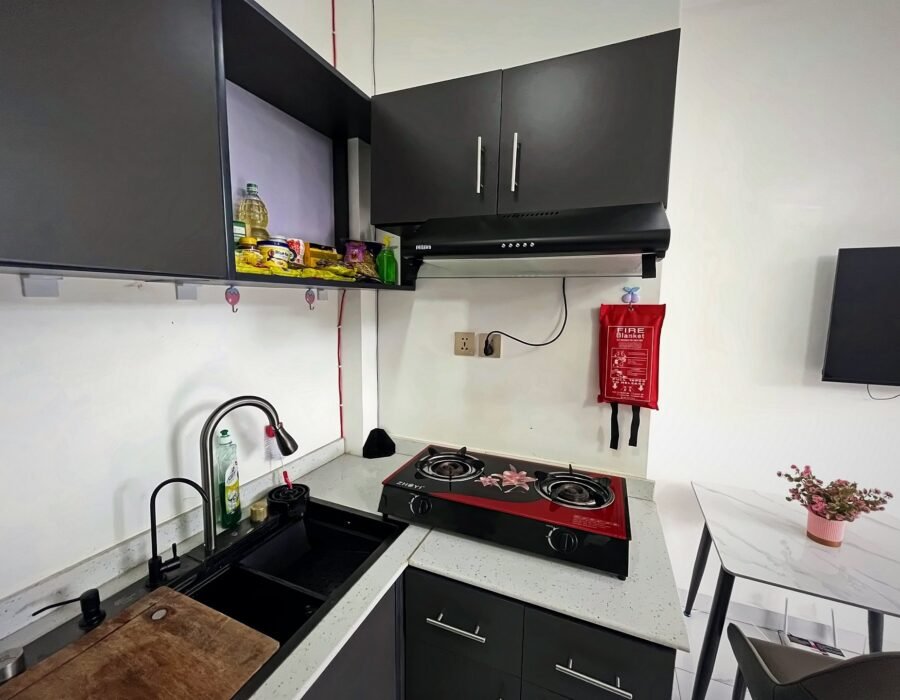Kitchen corner with a two-burner gas hob, extractor hood and sink at Holy Apartments, Kigali